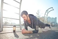 young man doing plank exercise outside